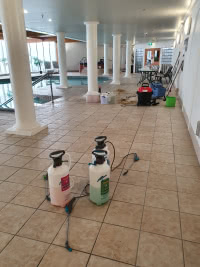 two chemical sprayers on tile floor next to indoor pool