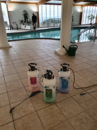 three chemical sprayers on tile floor next to indoor pool